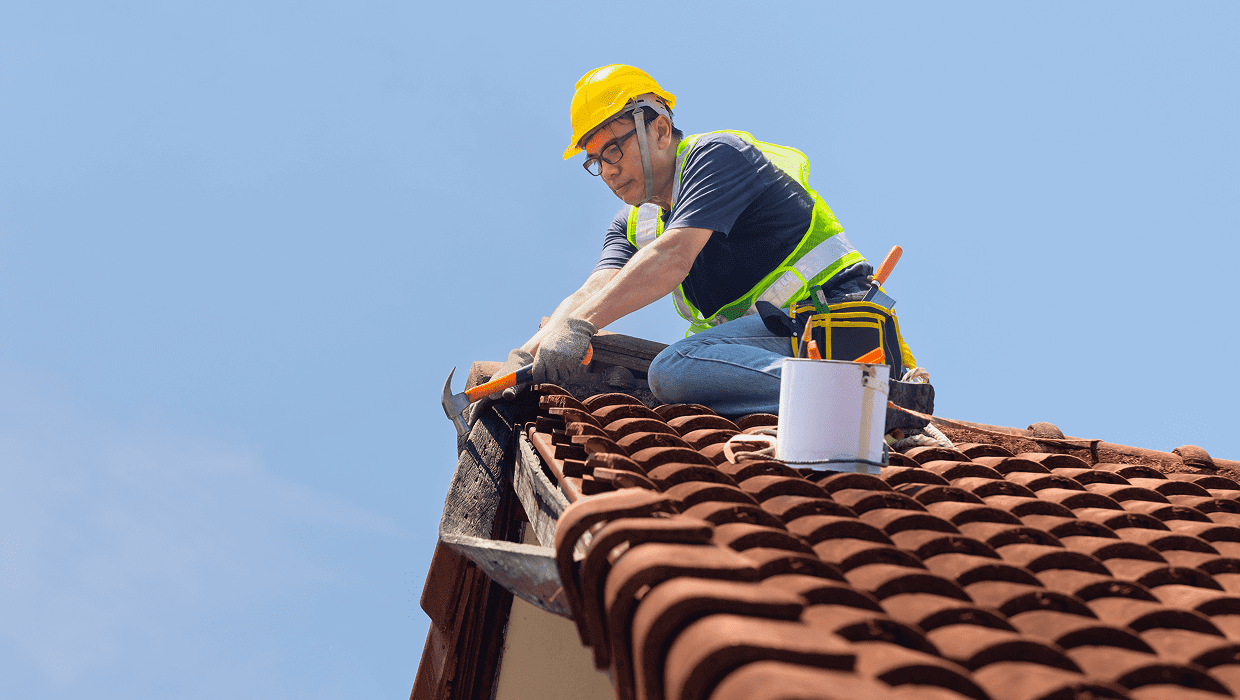 Roofer working on red tile roof.